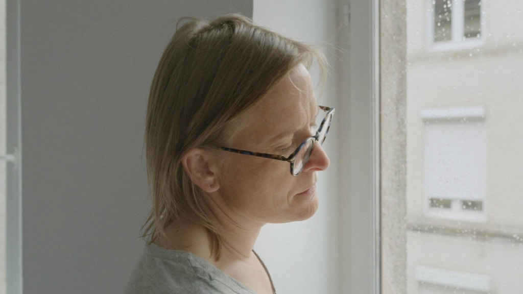 Sad woman in glasses gazes out of window