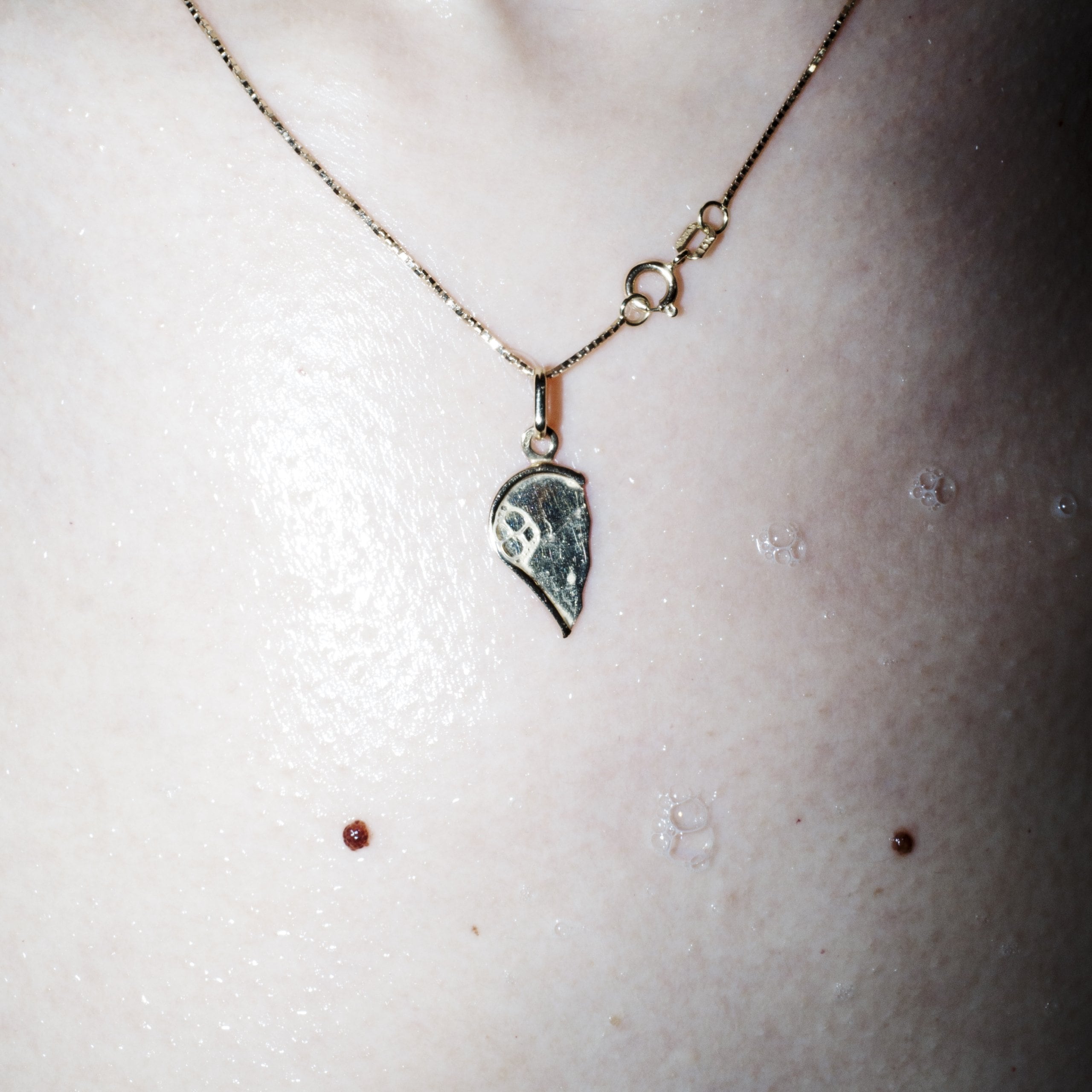 Closeup of a necklace with half a heart around Toma's girlfriends neck.
