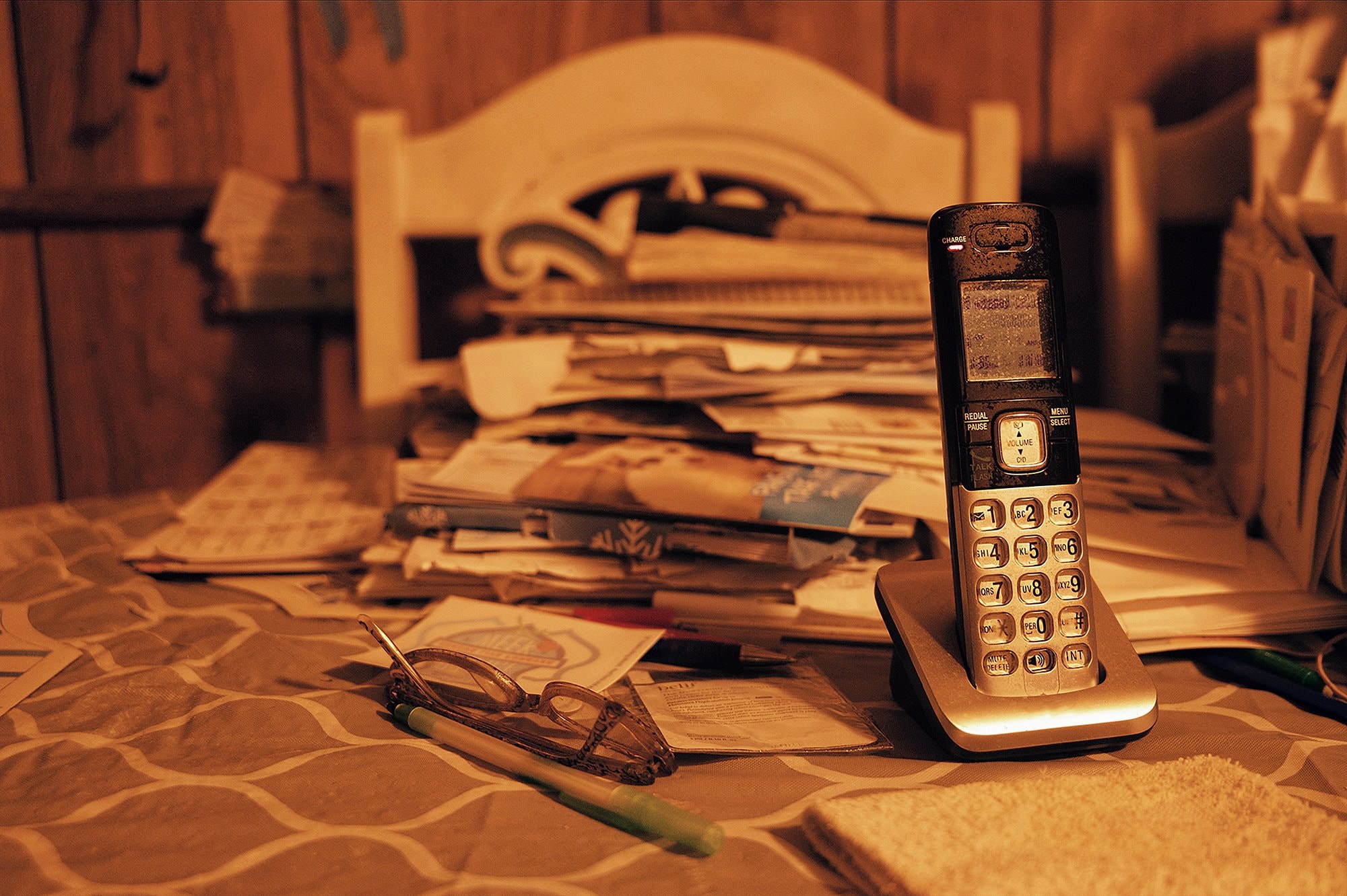 Closeup of a telephone and a stack of mail on a table.