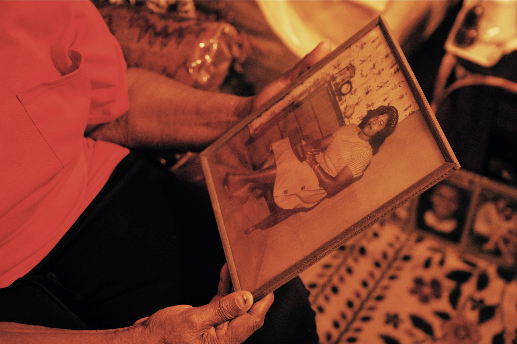 The lady sitting down holding a framed photo of a woman.