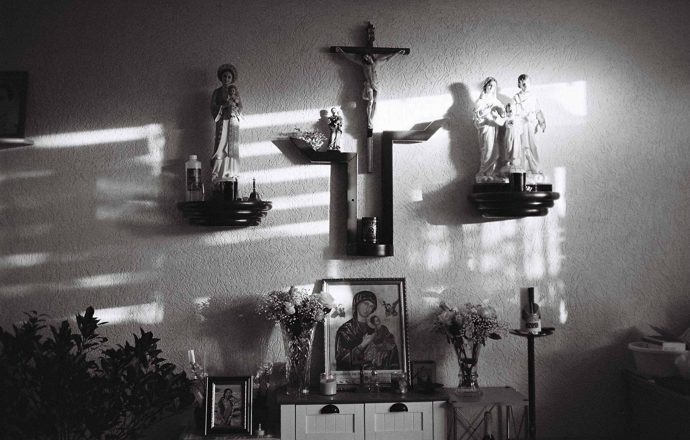 A wall with christian symbols, statues and pictures.