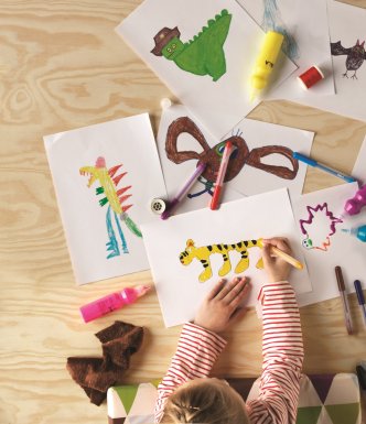 child drawing creatures on lots of different pieces of paper