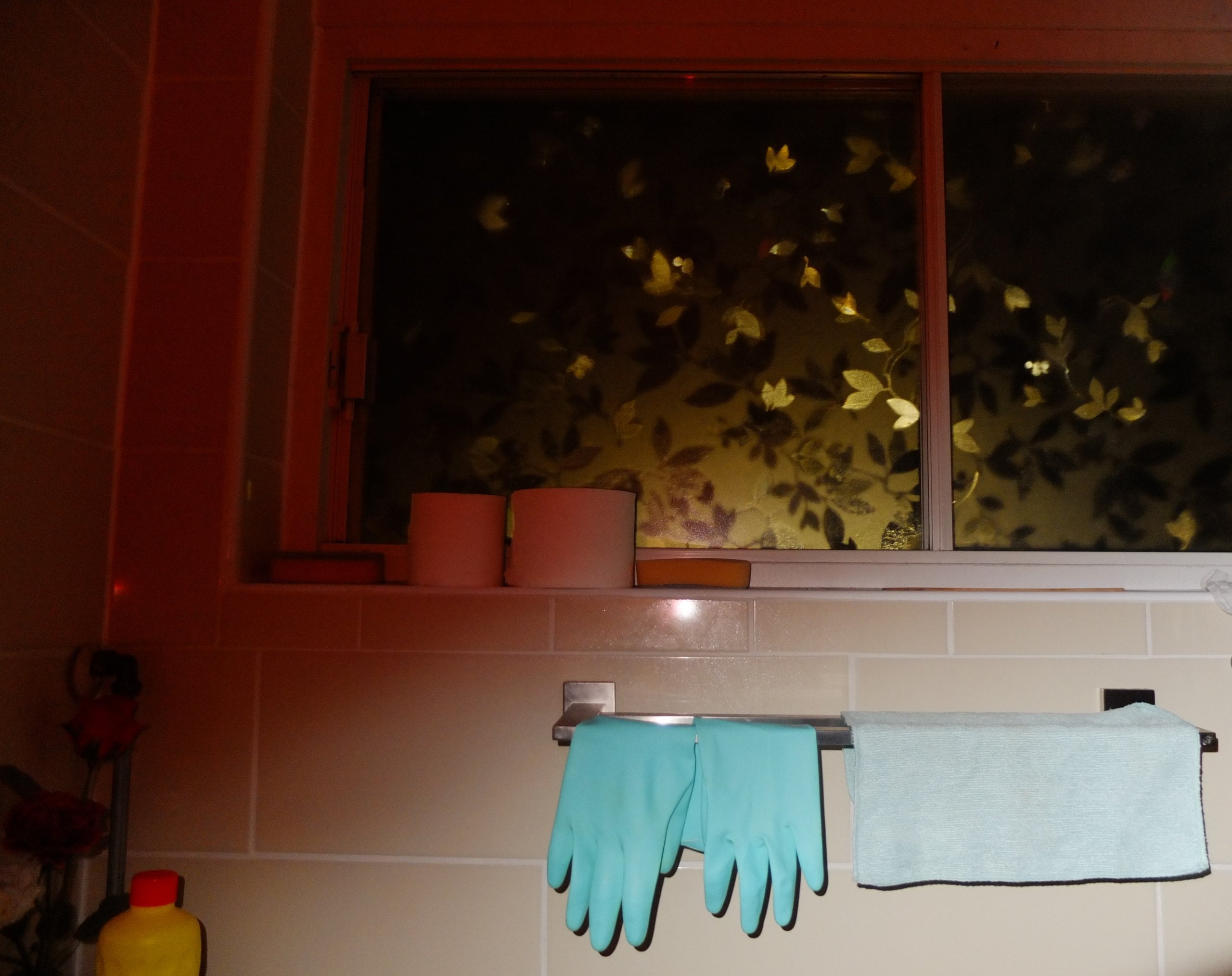 Rubber gloves and a wash cloth hanging on a bathroom rack.