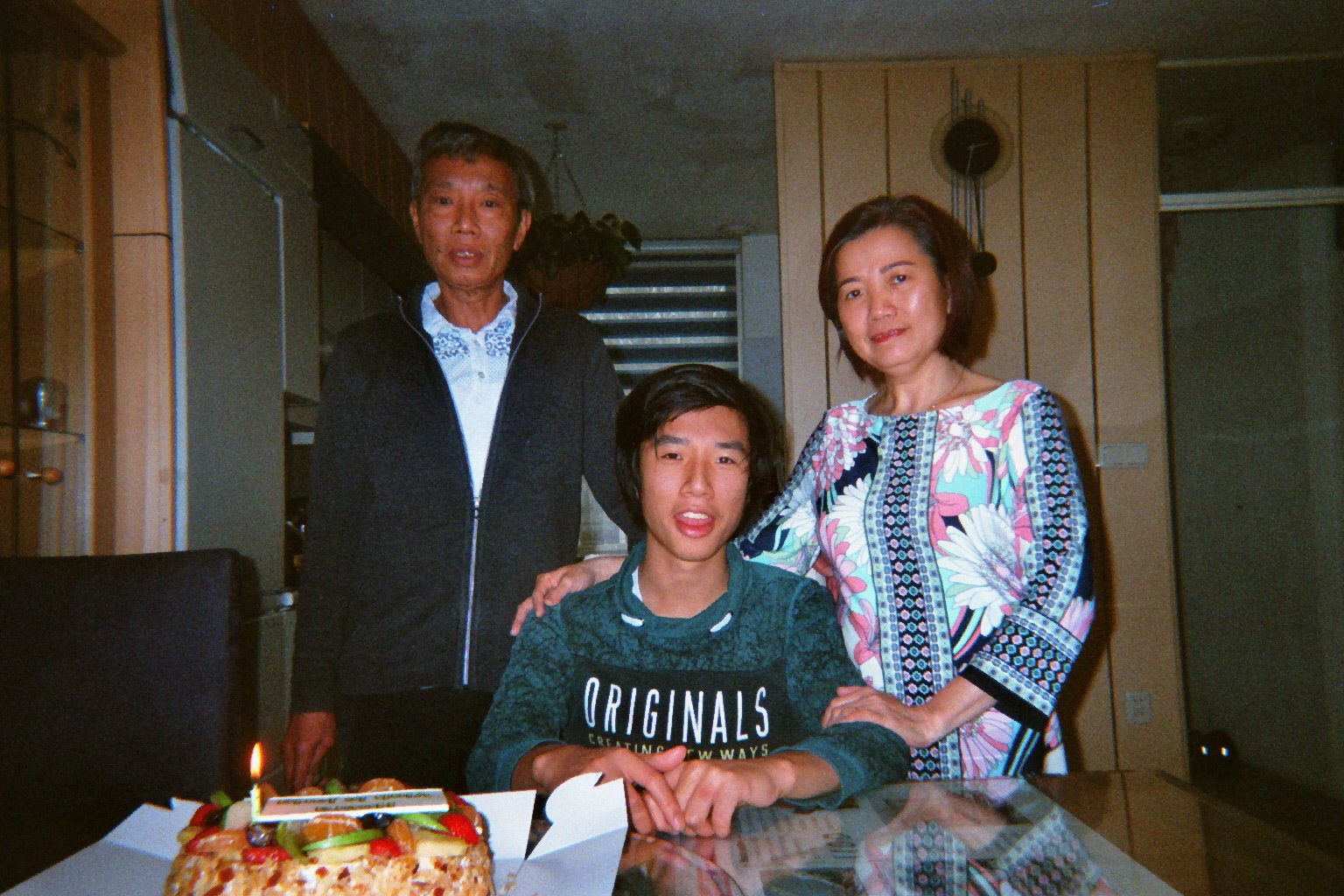 Trams father, brother and mother with a cake on the dining table.