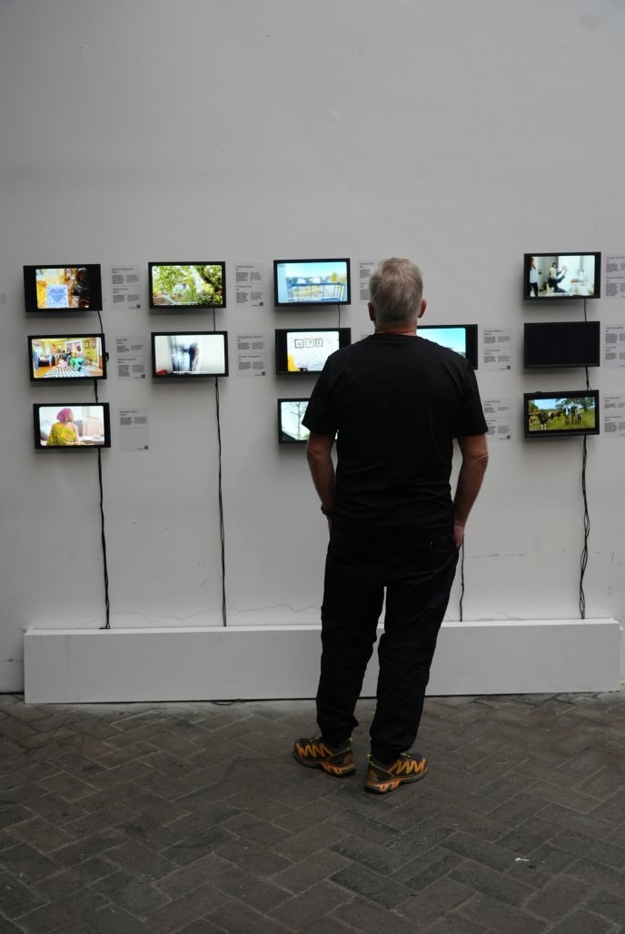 A man looking at images on small screens mounted to a wall at the exhibition.