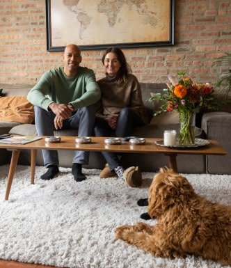 Smiling couple, sitting on their modern sofa with their dog at their feet