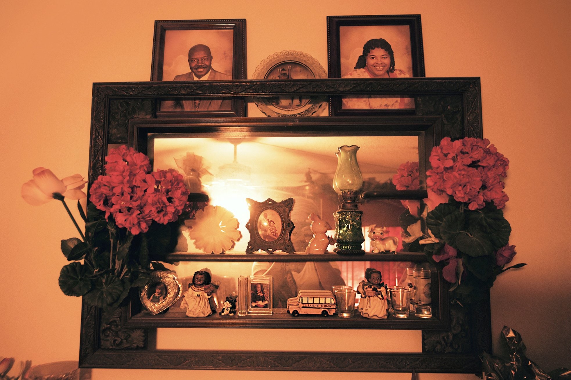 A shelf with mirror, family photos and small decorations.
